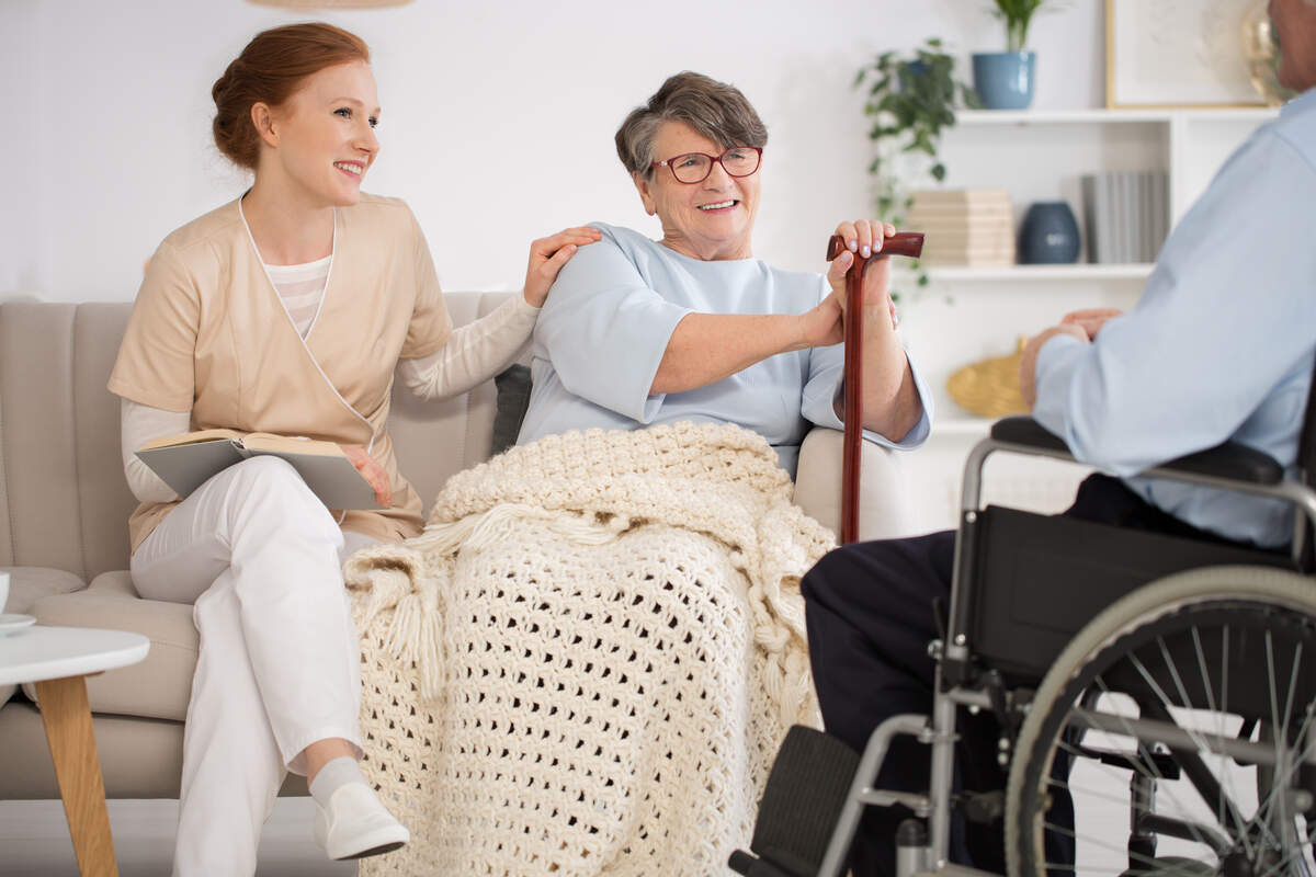 Respite Services & NDIS Short Term Accommodation Support - Beautiful nurse spending time with a disabled senior couple in a nursing home