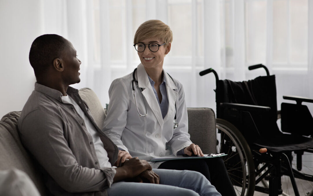 Specialist Disability Accommodation with Capability Care - Medical service, recovery and treatment at home or clinic. Happy doctor physiotherapist in white coat and glasses consultation to mature african american male disabled, sits on couch with wheelchair